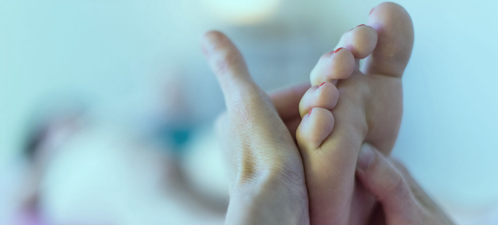 Hands performing reflexology on foot